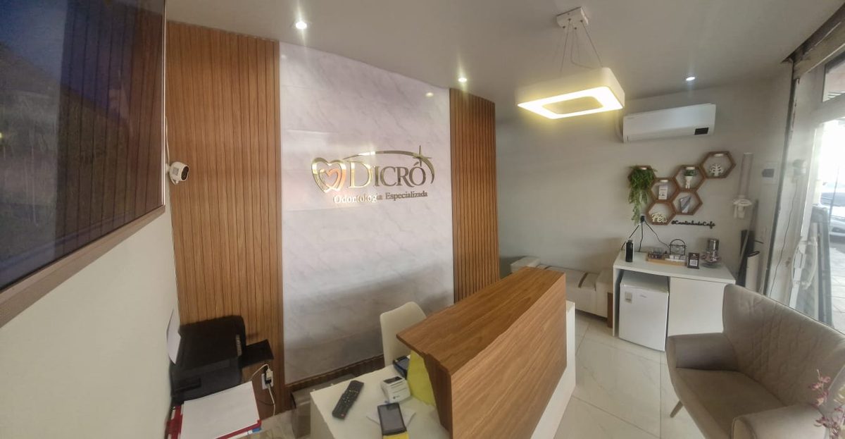 Recepção da Dicró Odontologia com logo dourado e cantinho do café em Mesquita/RJ